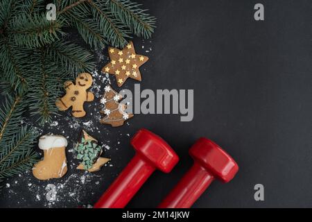 Lebkekse, Kurzhanteln, Weihnachtsbaumzweige. Diätzusammensetzung der Fitnessferien-Saison. Fitnessstudio, flache Diät mit Kopierbereich. Stockfoto