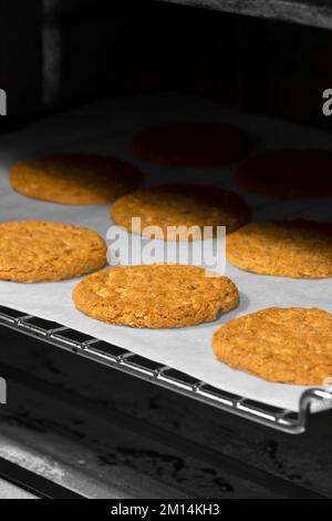 Haferkekse auf fettfestem Papier, das aus dem Ofen kommt, mit selektiver Farbe Stockfoto