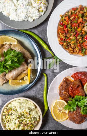 Top View traditioneller türkischer und griechischer Vorspeisentisch. Mediterranes Vorspeisenkonzept. Rohe Fleischbällchen, gerösteter Auberginen-Salat, gefüllte Oliven, Stockfoto