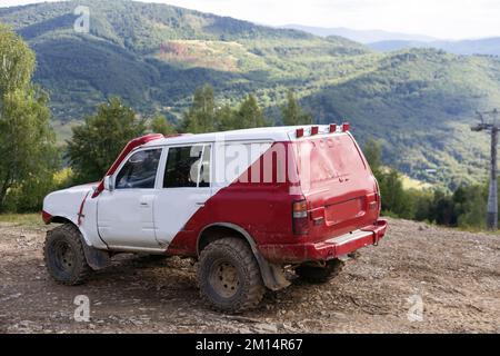 Alte Allradfahrzeuge fahren auf einer felsigen Bergstraße in vulkanischer Landschaft im Hintergrund Stockfoto