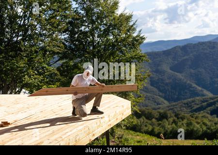 Reparatur-, Bau- und Heimkonzept - männliche Tragemutter mit Holzbrettern an der Schulter. Stockfoto