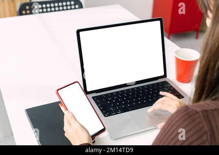 Modellbild eines jungen Menschen, der mit Laptop und Telefon arbeitet, mit weißem, leerem Bildschirm Stockfoto