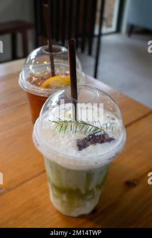 Grüner Eistee mit Milch und Zitronentee auf Holztisch, Stockfoto Stockfoto