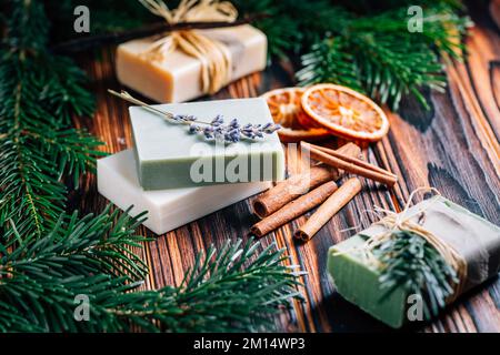 Natürliche organische Seifenriegel mit Orangen, Zimt und Lavendel auf Holzhintergrund Stockfoto