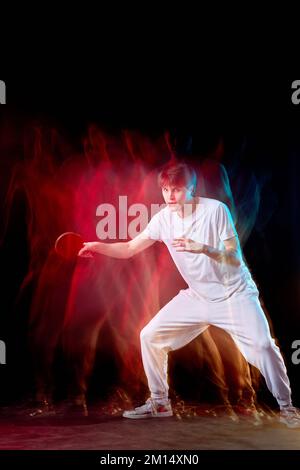 Junger Mann spielt Tischtennis in gemischtem Neonlicht Stockfoto