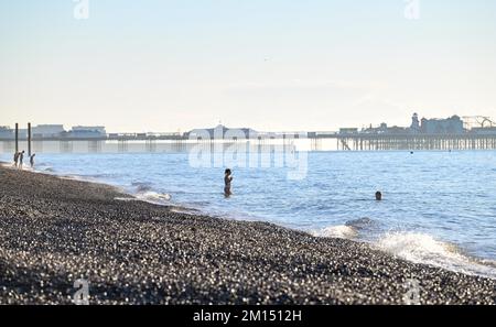 Brighton UK 10.. Dezember 2022 - Schwimmer genießen ein kühles Bad am Strand von Hove an einem wunderschönen sonnigen, aber frostigen Morgen, da die Temperaturen in einigen Teilen des Vereinigten Königreichs voraussichtlich minus 10 Grad erreichen werden : Credit Simon Dack / Alamy Live News Stockfoto