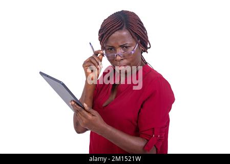 Eine schöne Geschäftsfrau, die auf weißem Hintergrund steht und ihre Brille anpasst, während sie ein Tablet hält und unglücklich aussieht. Stockfoto