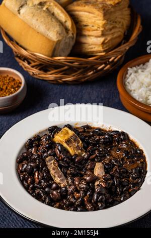 Bohnen und Schweinefleisch, typisch brasilianisches Essen, auf einem weißen Teller. Stockfoto