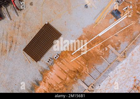 Lieferung von Stahlstangen aus Stahlbeton an Fundament mit Gabelstapler auf der Baustelle Stockfoto