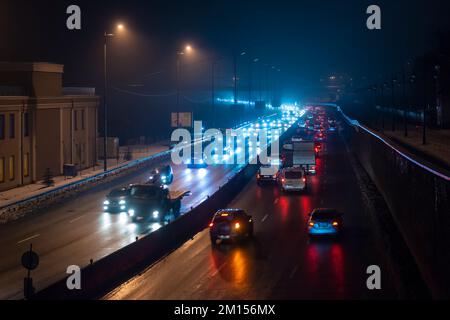 Autolichter in der nächtlichen nebeligen Stadt. Nachtverkehr Stockfoto