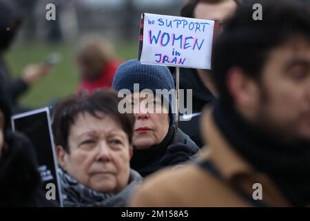 Berlin, Deutschland. 10.. Dezember 2022. Eine Frau hält ein Schild mit der Aufschrift "Wir unterstützen Frauen im Iran". Am Internationalen Tag der Menschenrechte demonstrieren die Menschen in Solidarität mit den Protesten im Iran am Brandenburger Tor. Kredit: Joerg Carstensen/dpa/Alamy Live News Stockfoto