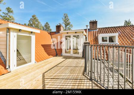 Ein Balkon mit einem orangefarbenen Ziegeldach und weißen Zierleisten um die Geländer, an einem Tag mit klarem blauem Himmel Stockfoto