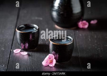 Starker japanischer Sake mit blühenden rosa Blumen. Traditionelles alkoholfreies Getränk in Japan. Stockfoto