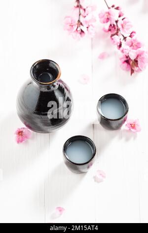 Traditioneller japanischer Sake mit blühenden rosa Blumen. Die Methode der Alkoholausschüttung in Japan. Stockfoto