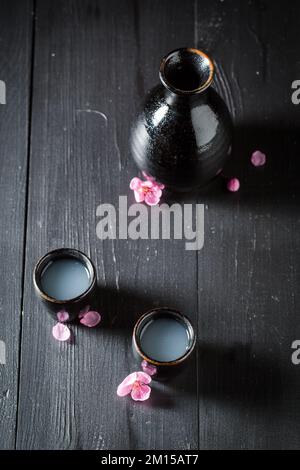 Einzigartiger japanischer Sake mit blühenden rosa Blumen. Traditionelles alkoholfreies Getränk in Japan. Stockfoto