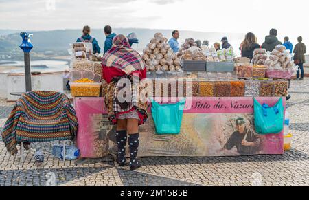 Nazare, Portugal - 09.12.2022: Frau in traditioneller Kleidung, die im Freien verkauft Stockfoto