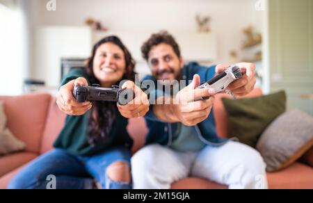 Ein junges, weißes Paar, das Spaß beim Spielen von Videospielen im Wohnzimmer hat Stockfoto