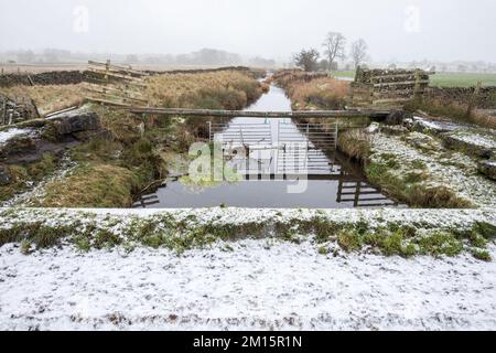 Brücke über den langen Preston Beck, der an ein Bauwerk angrenzt (etwas Wasser tropft), das unter dem Bett von Long Preston Beck zu führen scheint. Stockfoto