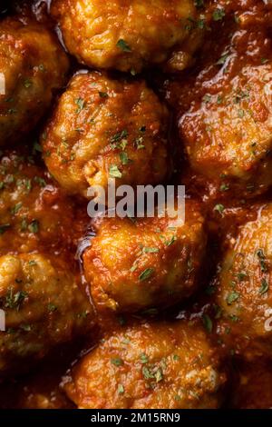 Voller Rahmen mit köstlichen Fleischbällchen in Tomatensoße mit Kräutern Stockfoto