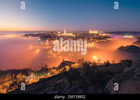 Von oben erstaunliche Landschaft der beleuchteten alten Alcazar de Toledo Burg über der Stadt in nebliger Dämmerung Stockfoto