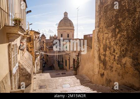 Malerischer Blick auf die antike Stadt Noto mit schmaler Straße zwischen alten Wohnhäusern und dem Dom-Turm an sonnigen Tagen Stockfoto