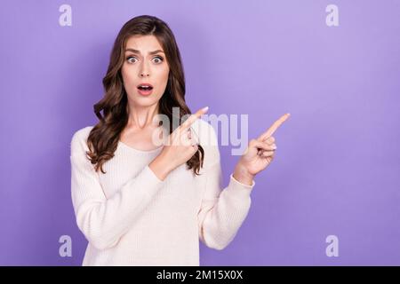 Foto einer lustigen, unglücklichen, unzufriedenen Grimace Lady lockig brünett Haarschnitt Finger zeigen leer Platz teurer Preis isoliert auf lila Farbe Stockfoto