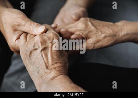 Gekürzter, nicht wiedererkennbarer älterer Mann, der seine ältere Frau emotional unterstützt und tröstet, während er ihre Hand hält Stockfoto