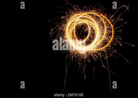 Kreise mit Funken auf schwarzem Hintergrund. Festliche Glitzer, abstrakte Silvesterlichter. Stockfoto