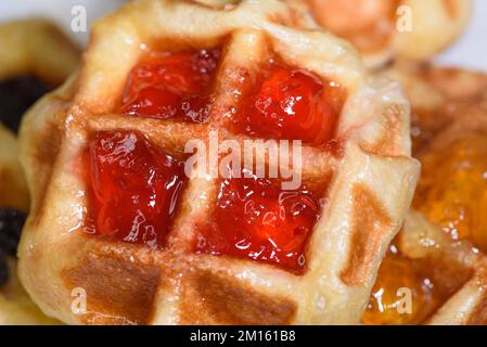 Nahaufnahme frischer Waffeln mit köstlicher süßer Erdbeermarmelade und Ananasmarmelade. Machen Sie selbst gemachte Speisen oder Snacks zu Hause Stockfoto