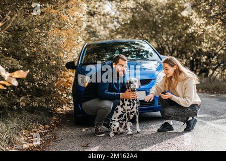 Mann mit Frau, viel Spaß mit ihrem Hund draußen im Wald in der Nähe des Autos. Stockfoto