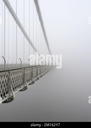 Ein einsamer Streuner, der die Clifton Hängebrücke in dickem Nebel überquert Stockfoto