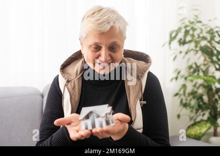 Eine glückliche maklerin, die ein kleines Hausmodell in der Hand hält, Handfläche, Objekt vor der Kamera zeigt, Agenturservice fördert, beim Haus hilft, Grundstückskauf Stockfoto