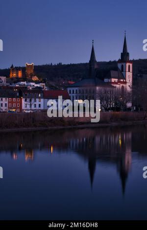 Bingen am Rhein, Deutschland - 10. Januar 2021: Kirche und Reflexion am Rhein mit Schloss Klopp auf einem Hügel im Hintergrund beleuchtet bei Nacht Stockfoto