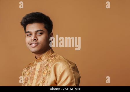 Ein junger brauner indianer, der lächelt und in die Kamera schaut, isoliert auf gelbem Hintergrund Stockfoto