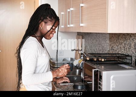 Schwarze Frau trinkt Kaffee in der Küche Stockfoto