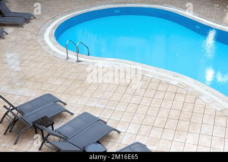 Blick auf den Pool und die Liegen von oben im Innenhof des Hauses Stockfoto