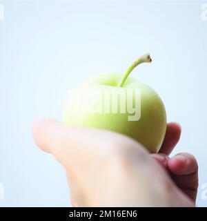 Frischer grüner Apfel in weiblicher Hand auf weißem Hintergrund. Stockfoto