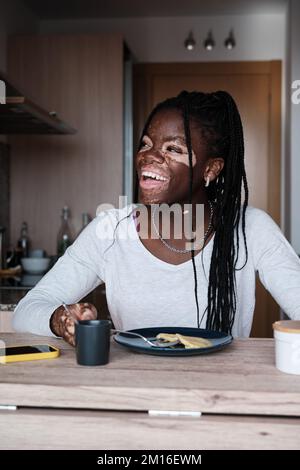 Glückliche schwarze Frau, die ein gesundes Frühstück in der Küche hat Stockfoto