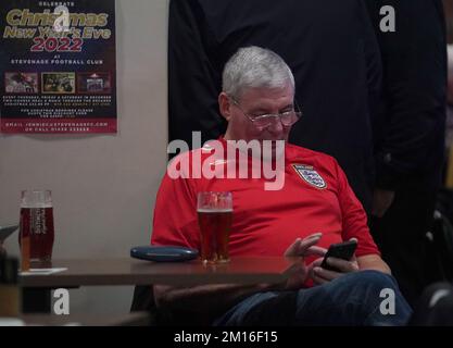 Ein englischer Fan schaut auf sein Handy in der 76 Lounge im Lamex Stadium, Stevenage, während er eine Vorführung des Viertelfinalspiels der FIFA-Weltmeisterschaft zwischen England und Frankreich sieht. Foto: Samstag, 10. Dezember 2022. Stockfoto