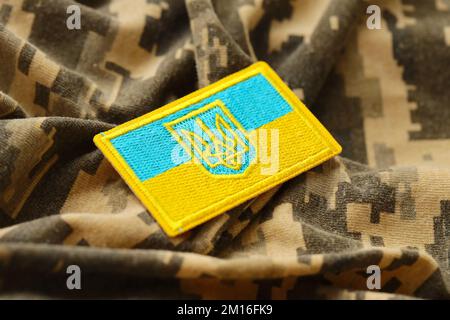 Pixeliges digitales Tarnmaterial mit ukrainischer Flagge und Wappen auf Chevron in Blau und Gelb. Attribute der ukrainischen Soldatenuniform Stockfoto