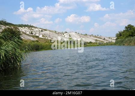 Antike multimillionäre Kreideberge auf der Steppenoberfläche der Erde. Weiße Kreideberge in einer Landschaft mit Fluss und grünen Bäumen Stockfoto