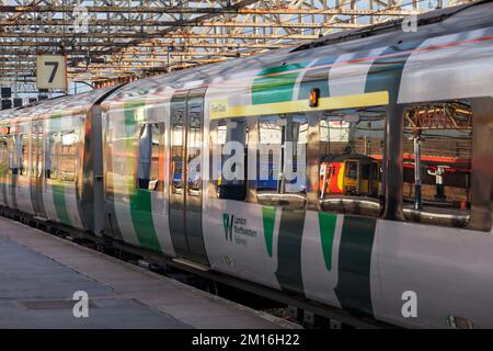 Der Zug der East Midlands Railway-Klasse 156 spiegelt sich im Fenster eines West Midlands Railway-Zuges der Klasse 350 am Bahnhof Crewe, Großbritannien, wider Stockfoto