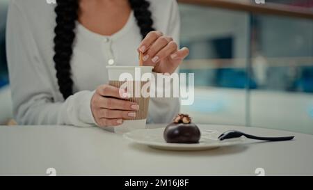 Eine unbekannte Kundin, eine Studentin, sitzt im Café-Restaurant und rührt Zucker in Latte-Kaffee, Getränk heißes Koffein, Getränk, Espresso, Cappuccino, Essen Stockfoto