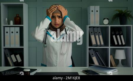 Kranke arabische muslimische Frau überlastet müde medizinische Arbeiter Arzt Arzt leiden an Kopfschmerzen Berührungskopfmassage Schläfen Unwohlsein Schmerzen chronisch Stockfoto