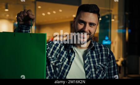 Glücklicher Kunde arabischer hispanic-Käufer Käufer Shopaholic steht in einem Einkaufszentrum und kauft trendige Kleidung im Boutique-Shop. Bewahren Sie Geschenktüten auf Stockfoto