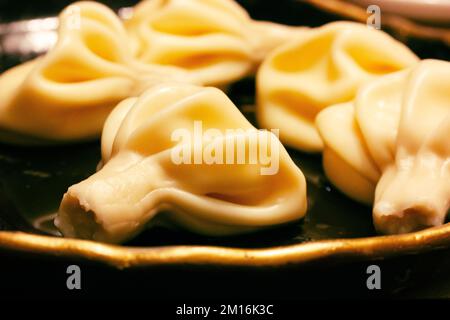 Köstliches gekochtes Khinkali auf einem schwarzen Teller aus nächster Nähe. Georgianisches Kochkonzept. Lebensmittelhintergrund. Georgische Knödel. Stockfoto