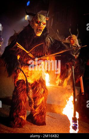 Maskierte Teufelsbiester paradieren durch das Dorf und erschrecken die Menge, während diese folklorische alpine Tradition am Leben erhalten bleibt Stockfoto