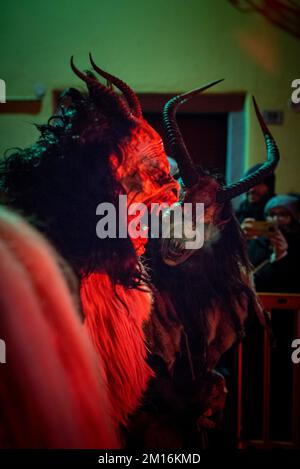 Maskierte Teufelsbiester paradieren durch das Dorf und erschrecken die Menge, während diese folklorische alpine Tradition am Leben erhalten bleibt Stockfoto