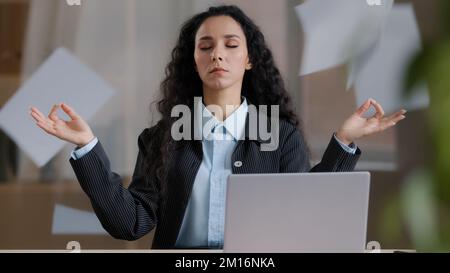 Ruhige achtsame weibliche Geschäftsfrau in Lotusposition, die Pause macht Meditationshintergrund des Werfens von Papieren, die yogische Atemübungen machen, Feelin Stockfoto