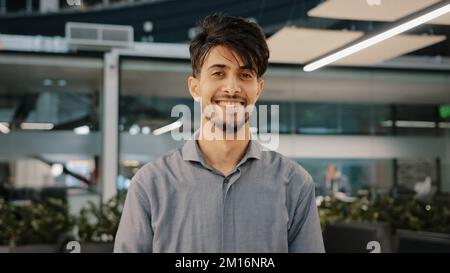 Happy indian bärtig schöner Erwachsener Mann stehen in Halle Büro lächelnd Blick auf Kamera fröhlich männlich arabisch brünette Kerl Geschäftsmann verwalten Stockfoto